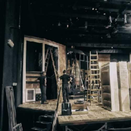 Pracownicy na scenie teatralnej podczas montażu